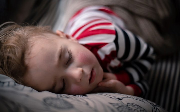 A little boy peacefully sleeping on a sofa