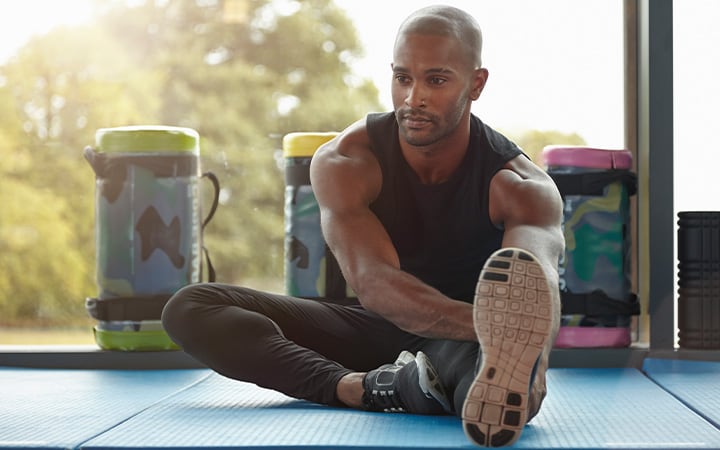 A man stretching his hamstrings in the gym