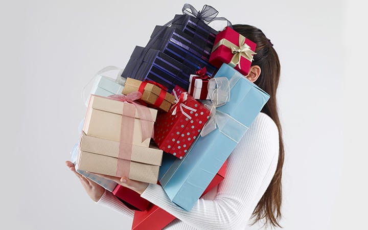 Woman carrying too many gift boxes
