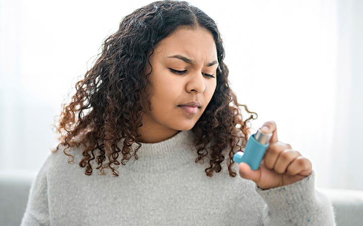 A woman taking her inhaler at home at the living room