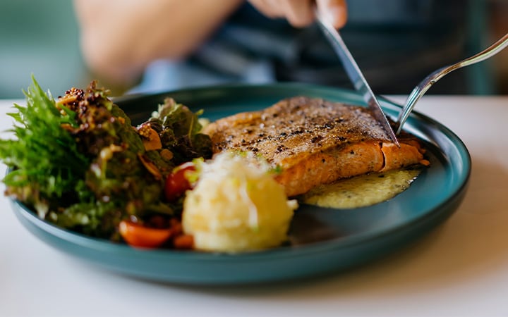 Woman eats salmon and vegetables