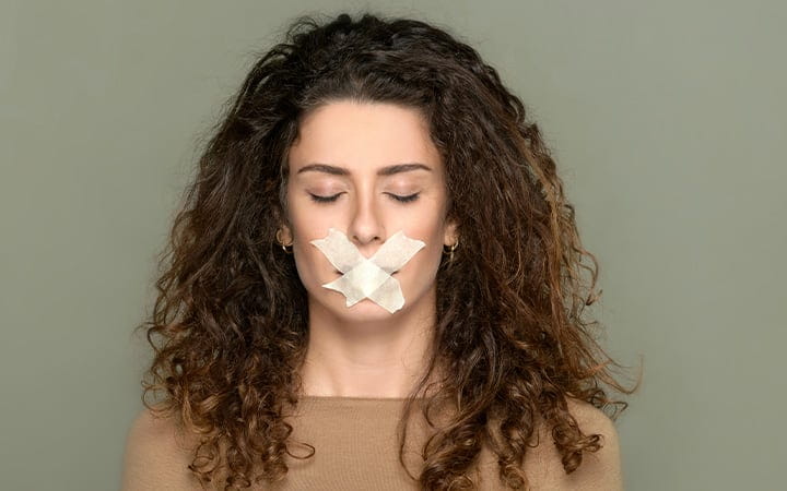 A young woman with closed eyes and taped lips
