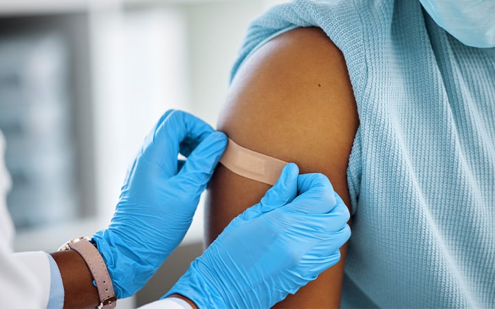 A doctor applying a sticking plaster to her patient's arm