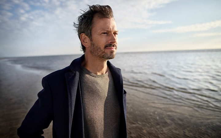 Man at the beach looking thoughtful