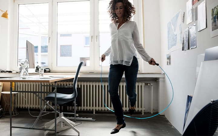 Businesswoman in office, training with skipping rope