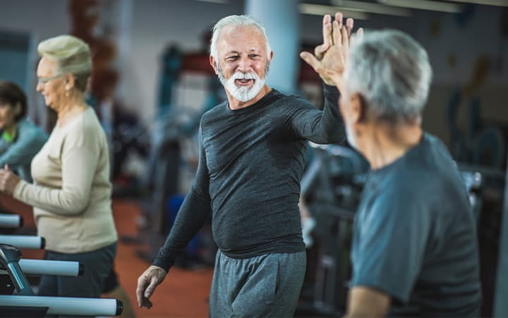 Men on treadmill high five each other