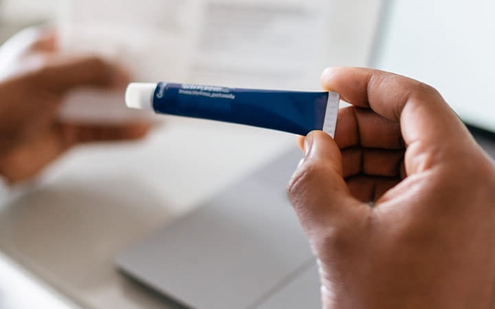 A man holding a tube of prescription steroid cream