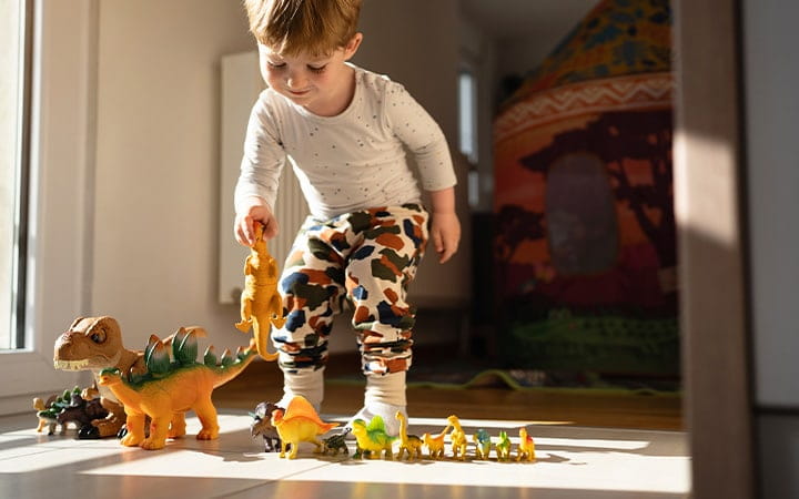 A toddler boy playing with dinosaur toys
