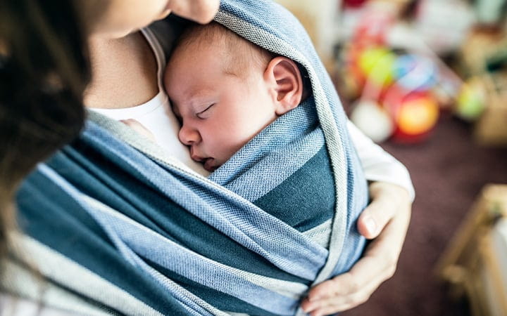 A young mother with her newborn baby son in a sling