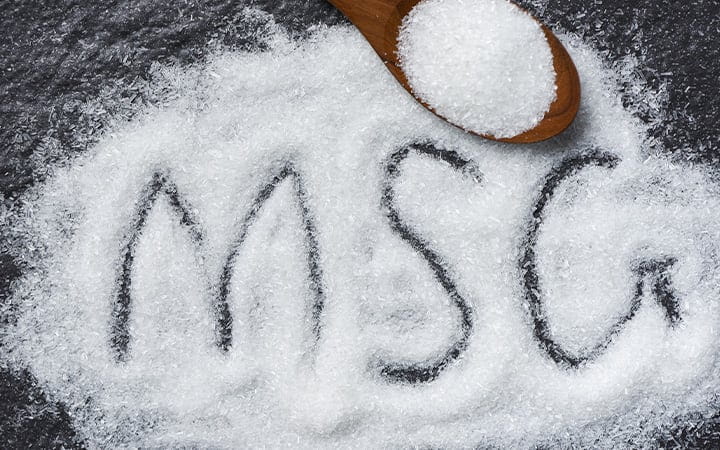 Heap of monosodium glutamate on wooden spoon