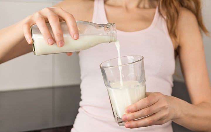 woman pours milk into glass