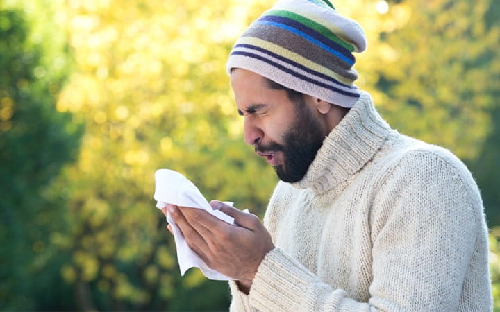 Man sneezing outdoors
