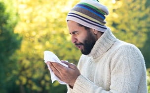 man sneezing outdoors