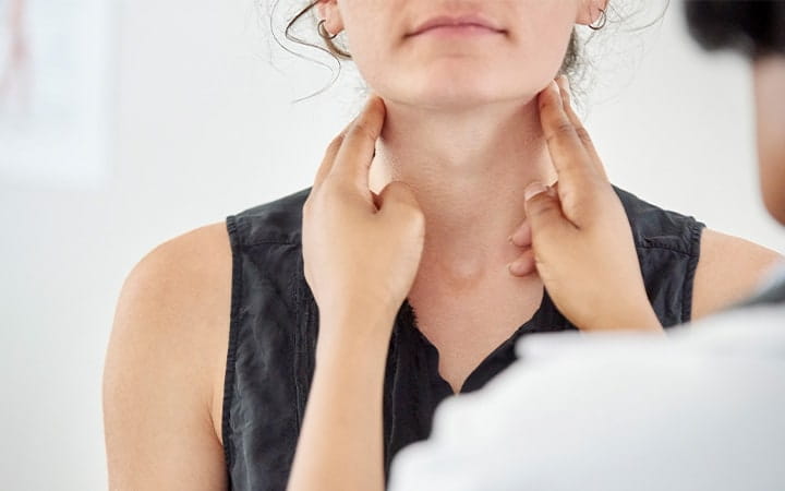 Close-up of a female doctor checking thyroid of a young female patient