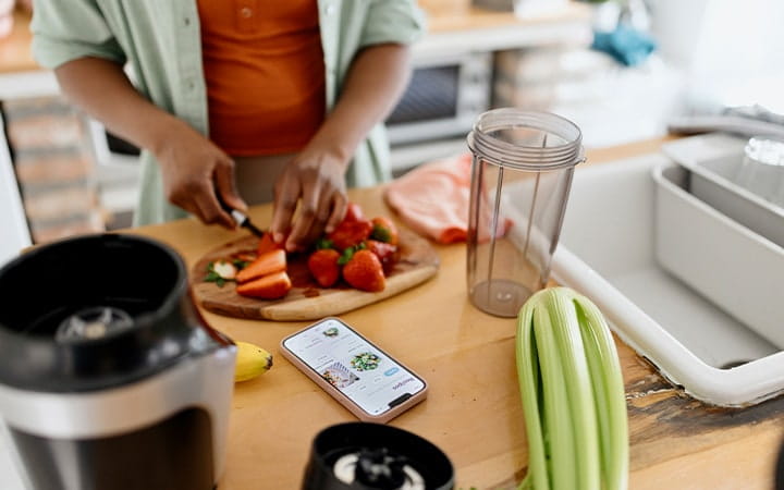 Woman blending a delicious and healthy smoothie with strawberries, bananas, celery, and water