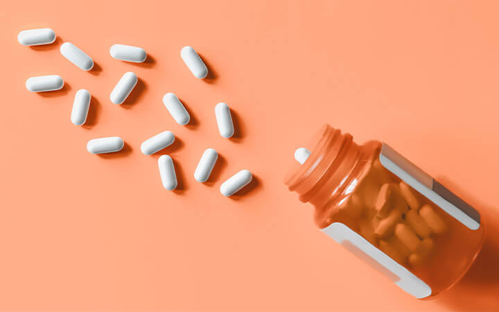 White pills spilling out of prescription bottle