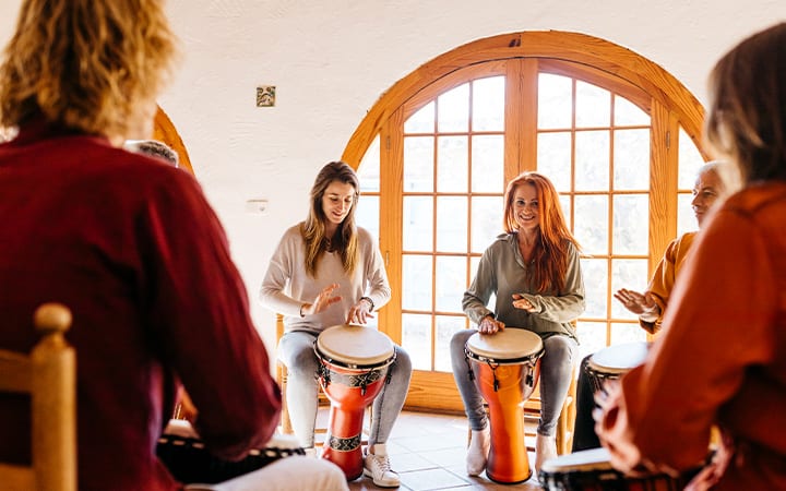 Smiling friends playing bongo at music therapy