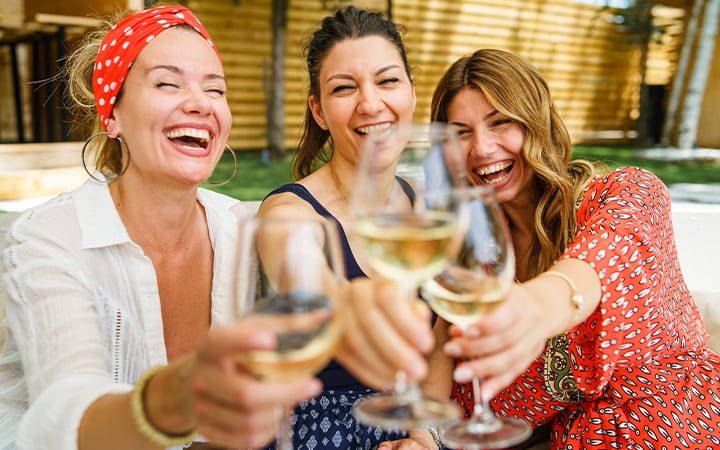 Three women drinking white wine on a sunny day