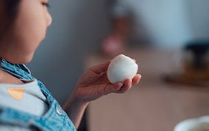 A young girl holds a hard boiled egg in her hand