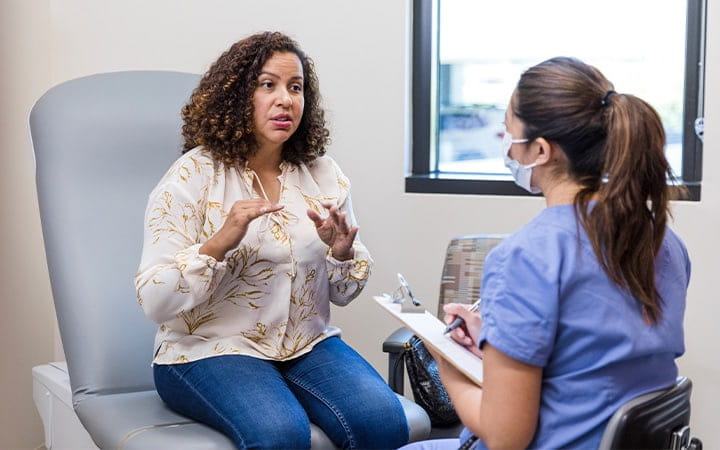 A female patient explains symptoms she has been experiencing to her doctor
