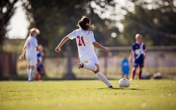 A female soccer player kicking the ball during a match