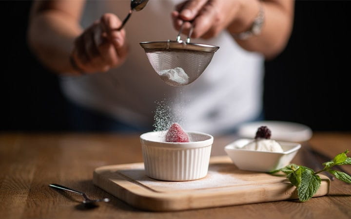 A chef sprinkling powdered sugar on chocolate souffle