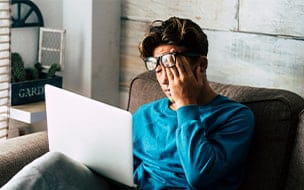 A tired teenager at home studying with a personal laptop computer