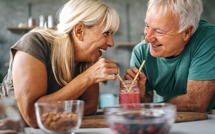 Loving senior couple drinking healthy smoothie in the kitchen at home