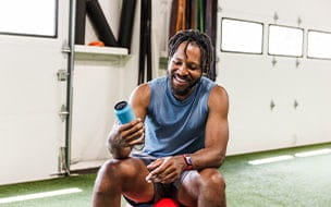 A smiling man holding an energy drink while sitting at health club