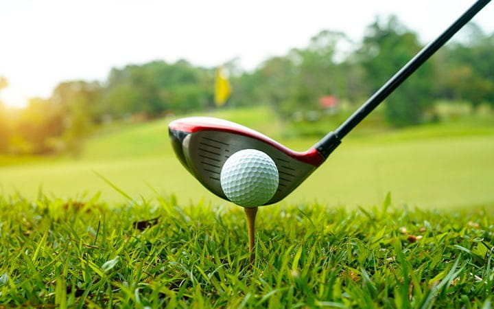 Golf ball and golf club at a beautiful golf course at sunset