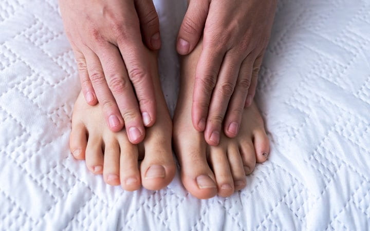 A woman's hands caressing her two feet in pain
