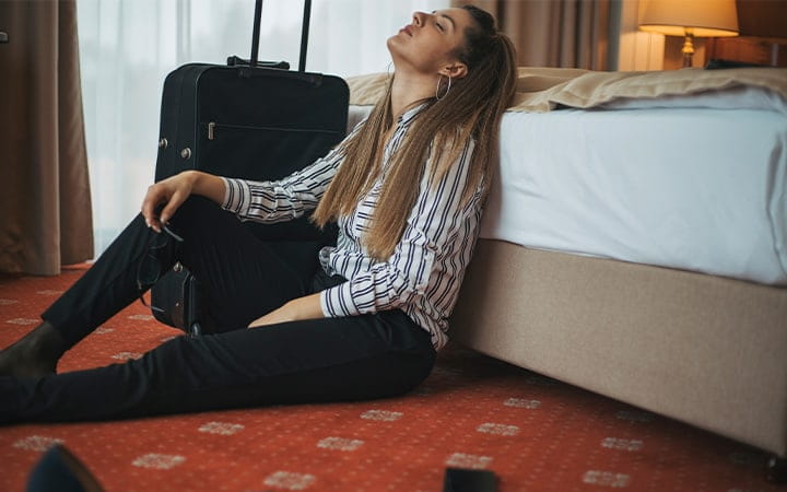 Woman with luggage sitting on hotel room floor