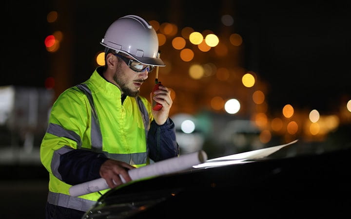 An electrical engineer communicates with his team via walkie-talkie at night