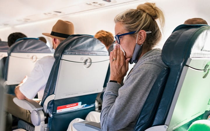 Woman on airplane blowing her nose