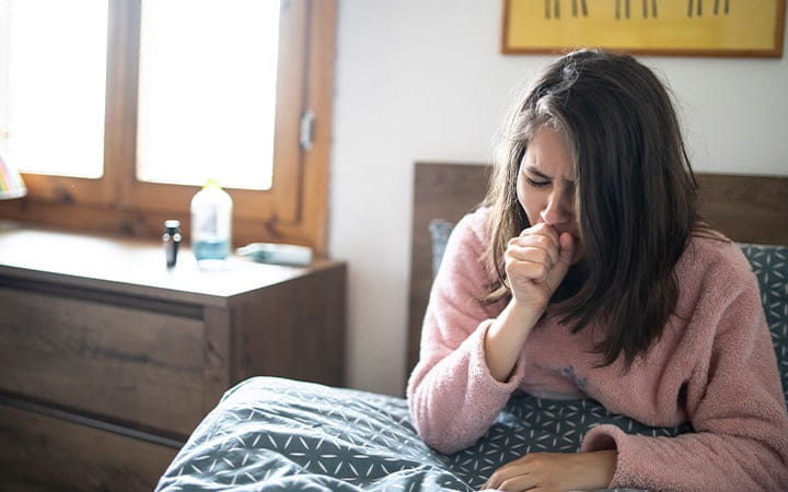 Teen girl coughing in bed
