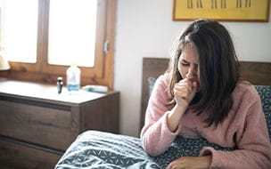 Teen girl coughing in bed