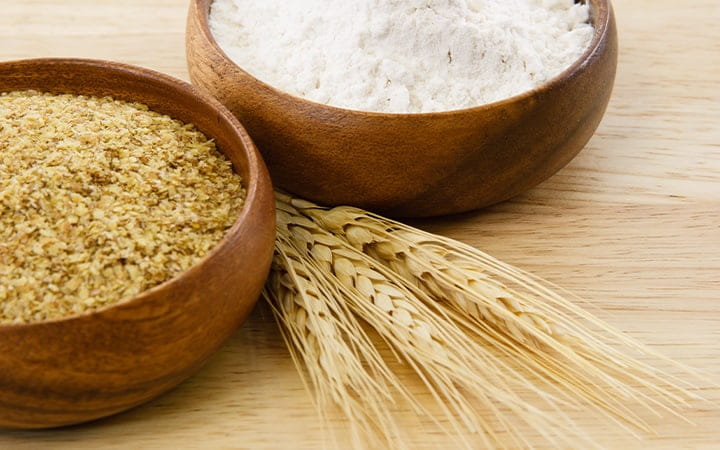 Two wood bowls with flour and wheat germ
