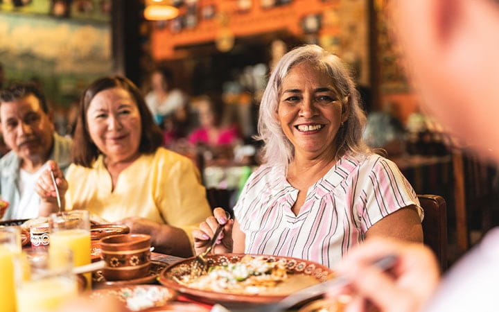 Happy senior friends talking and eating at restaurant