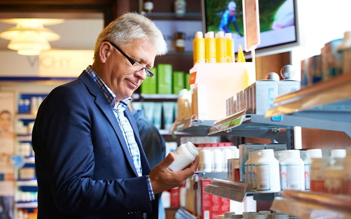 Older man looking at pill bottle label