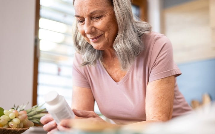 Older woman reading label on pill bottle