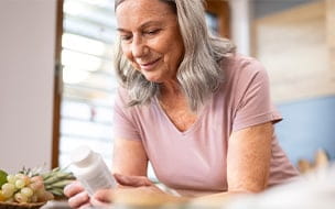 Older woman reading label on pill bottle