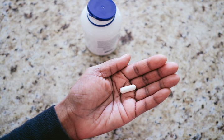 A woman holding a nutritional supplement capsule in the palm of her hand