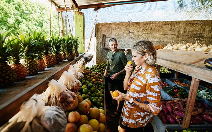 A smiling woman smelling fruit while shopping at a local market during vacation