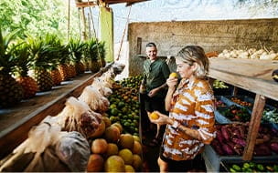 A smiling woman smelling fruit while shopping at a local market during vacation