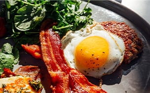 Keto breakfast with fried egg, bacon, cheese, ground beef and salad