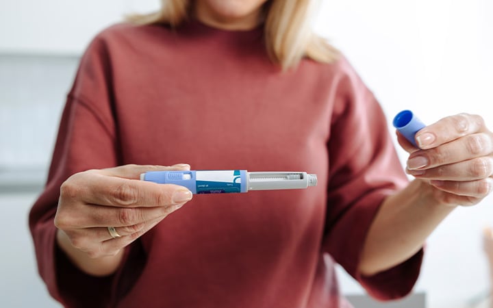 A person holding and preparing a medical injection pen