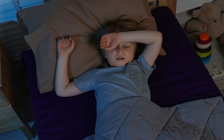 A little boy snoring while sleeping in bed at night