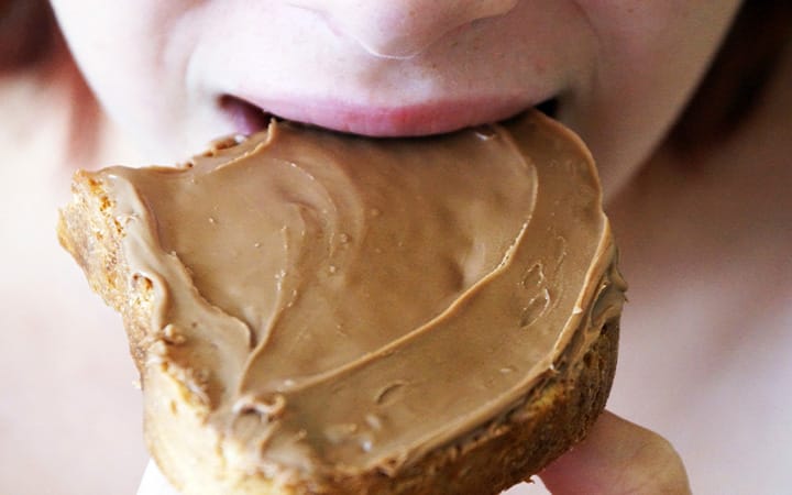 A young girl biting into a peanut butter sandwich