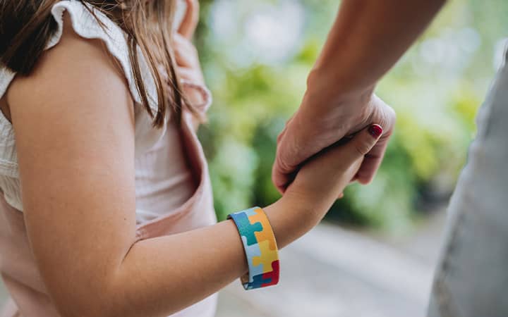 An autistic child holding hands with her mother