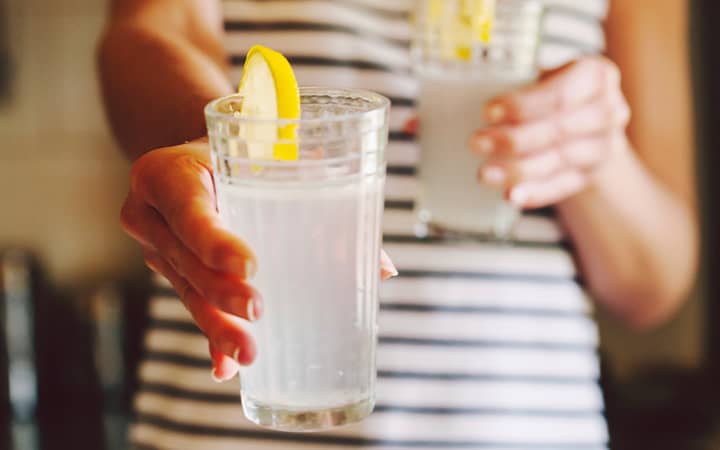 A woman holding glasses of fresh lemonade